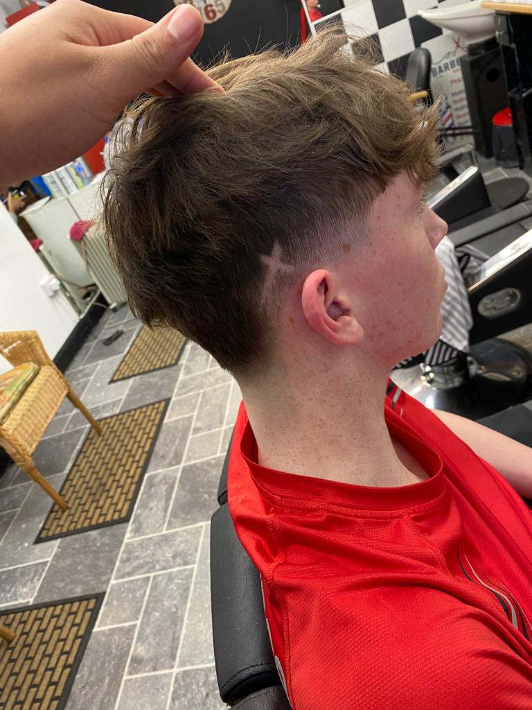 Boy wearing red shirt with a nice new hair cut with a cross shaped bit in his hair