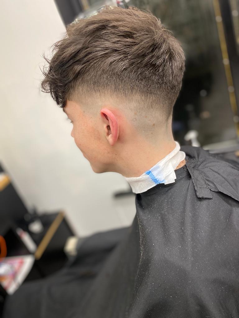 Angled picture of boy with a fade and a slightly longer top